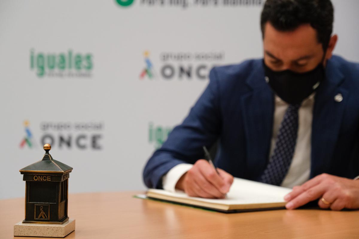 Juanma Moreno firma en el libro de honor de visitas de la Delegación Territorial