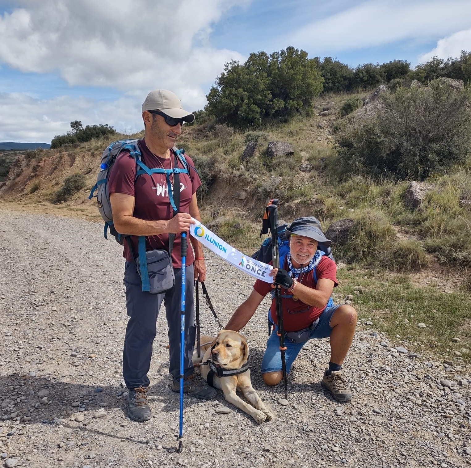 Los dos caminantes mostrando orgullosos una cinta de Ilunion y Grupo Social ONCE