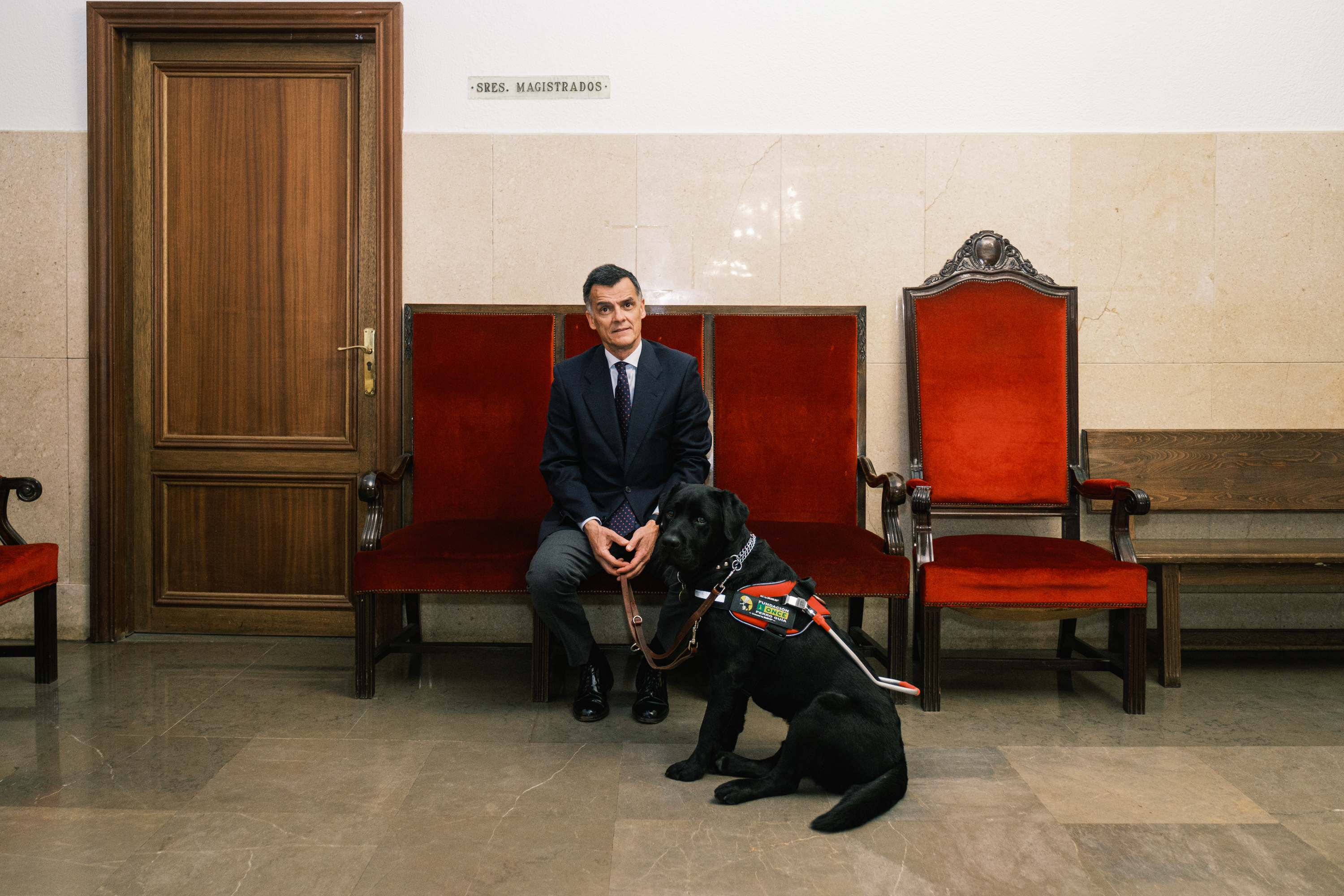 El juez sentado en un banco con su perro guía sentado también
