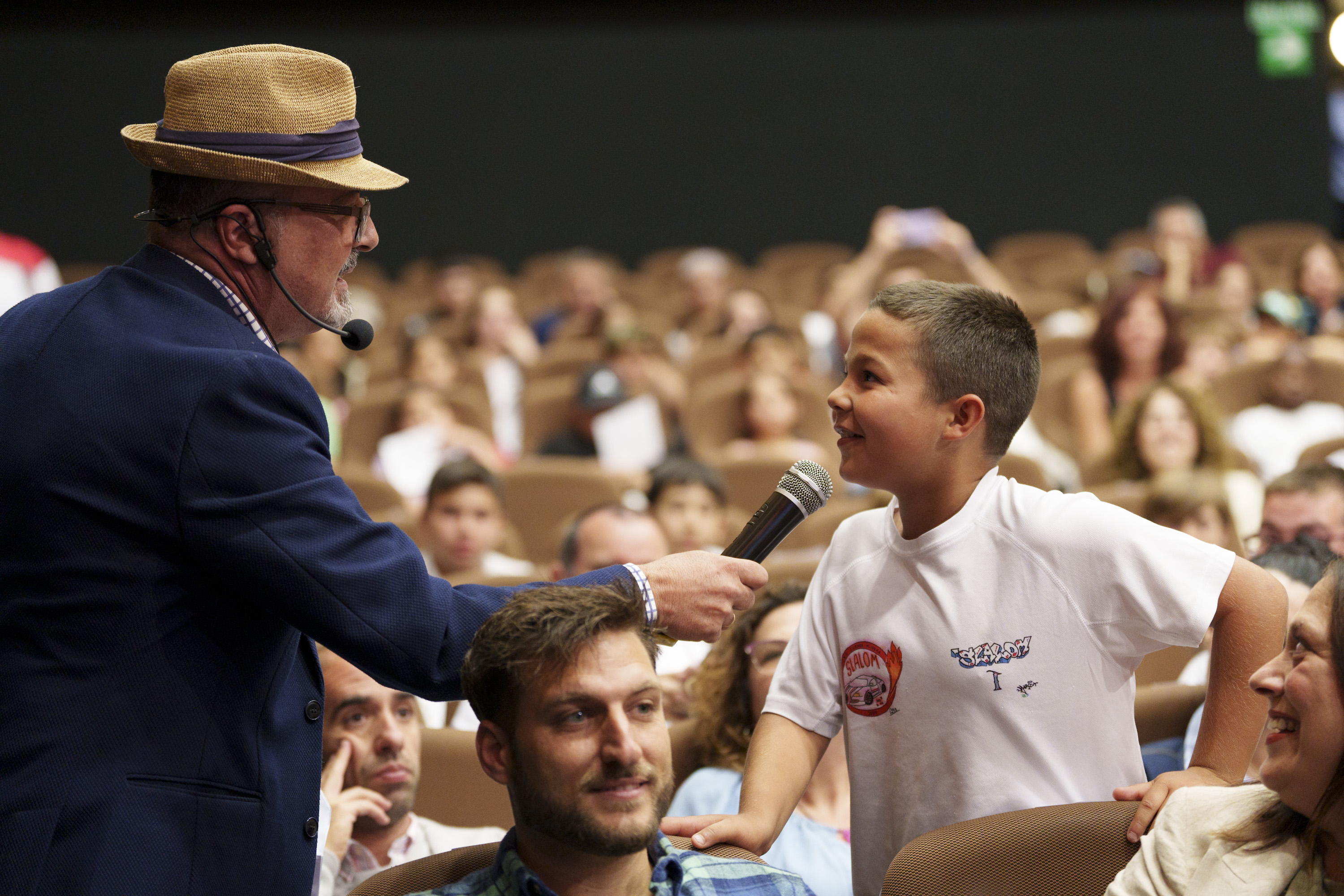 El presentador hace una pregunta a un niño del público