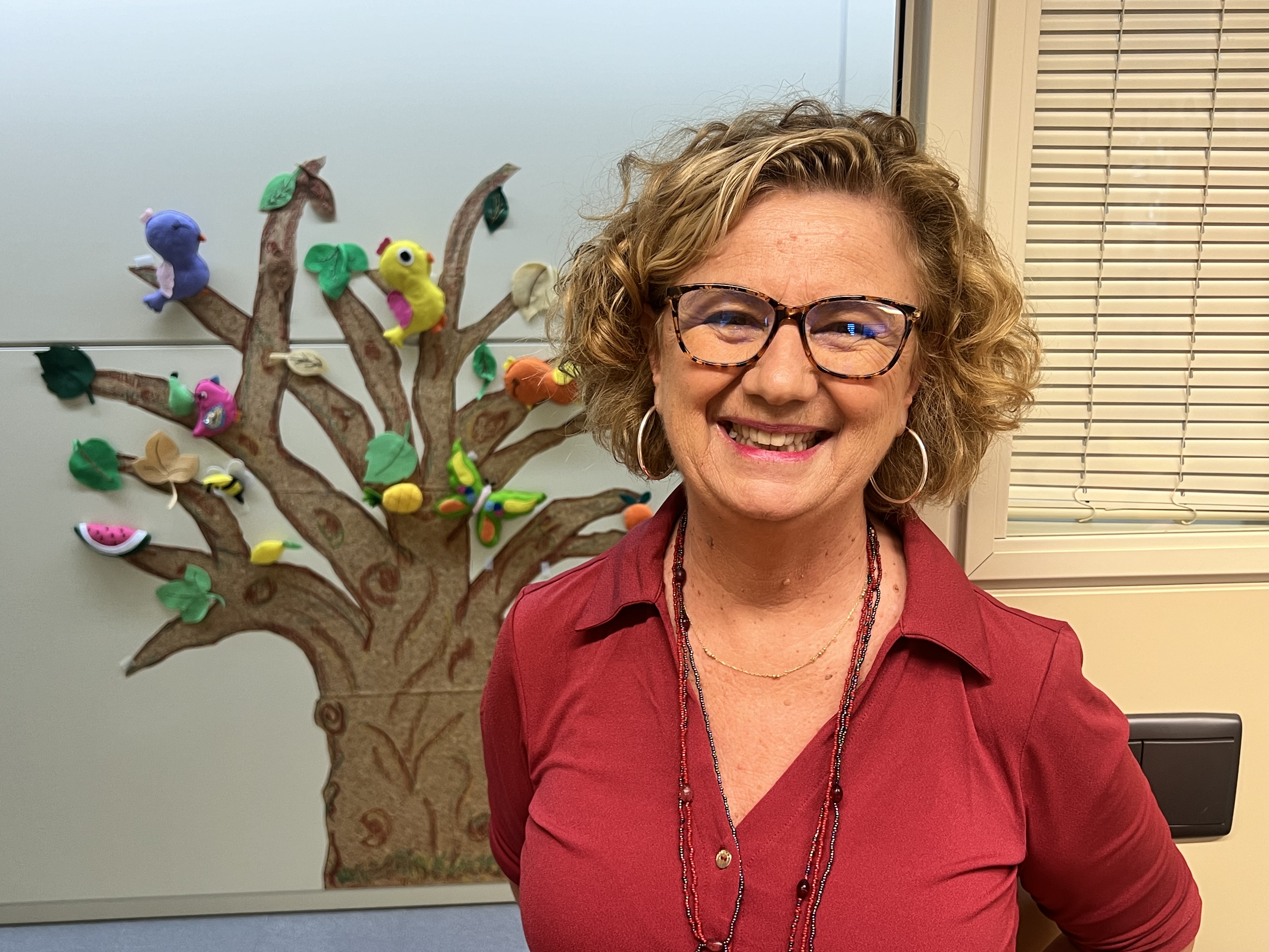 Cristina junto a un árbol elaborado por los alumnos en el pasillo del CRE