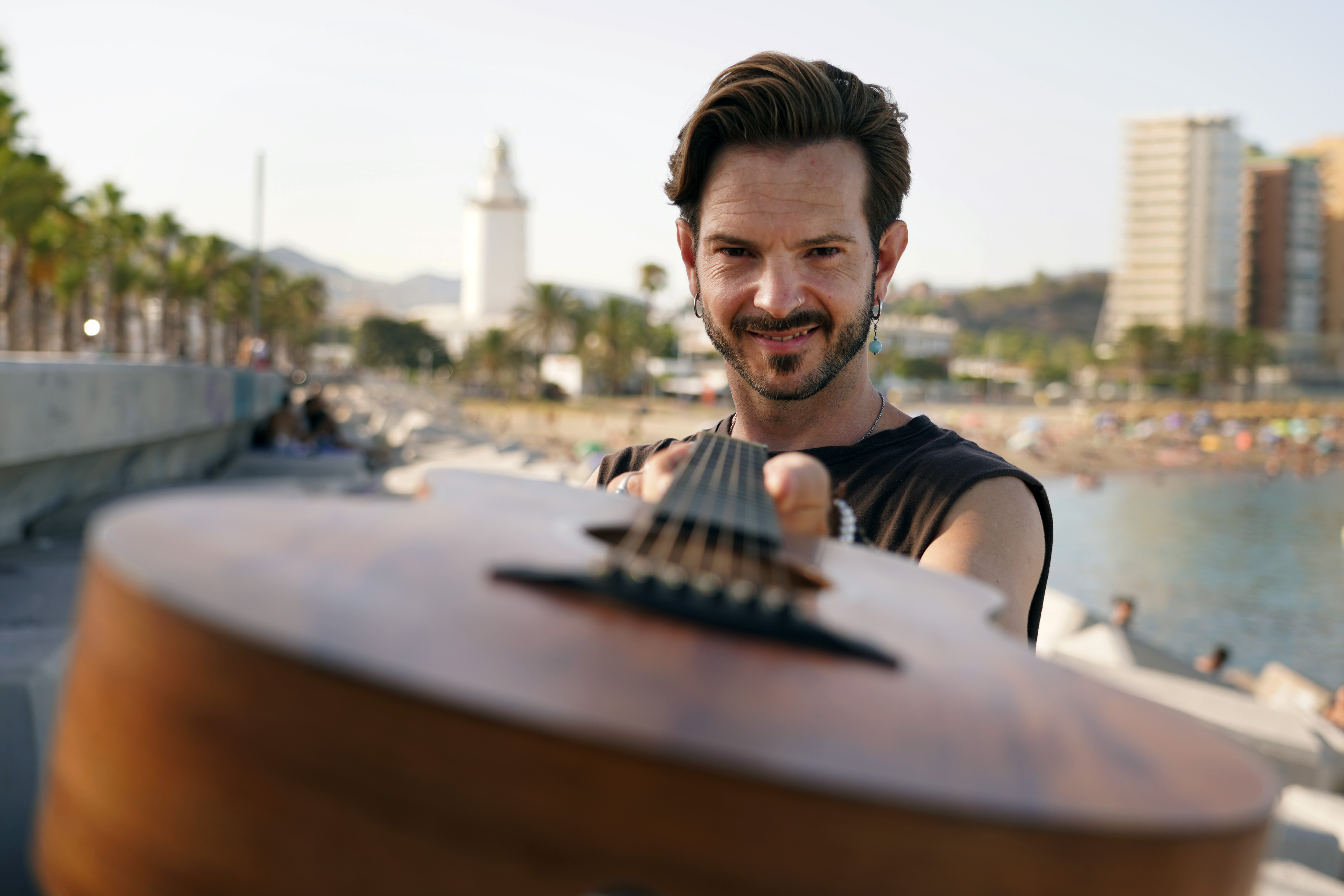 Joaquín con su guitarra en primer plano y el fondo de la playa de La Malagueta