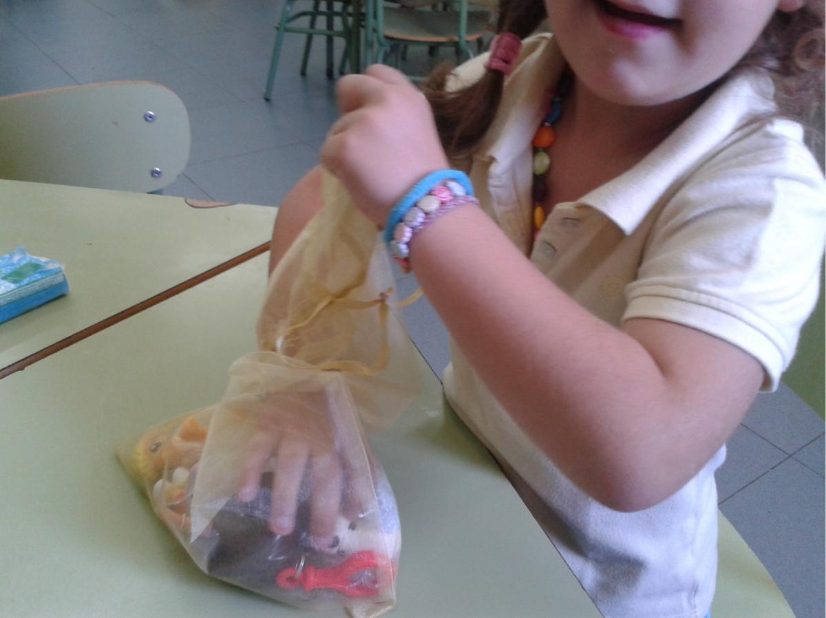 Una niña mete las manos en una bolsita donde están los materiales del cuento