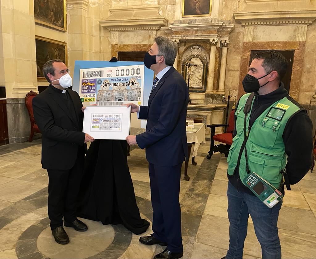 El director de la ONCE en Cádiz entrega la imagen del cupón al deán de la catedral