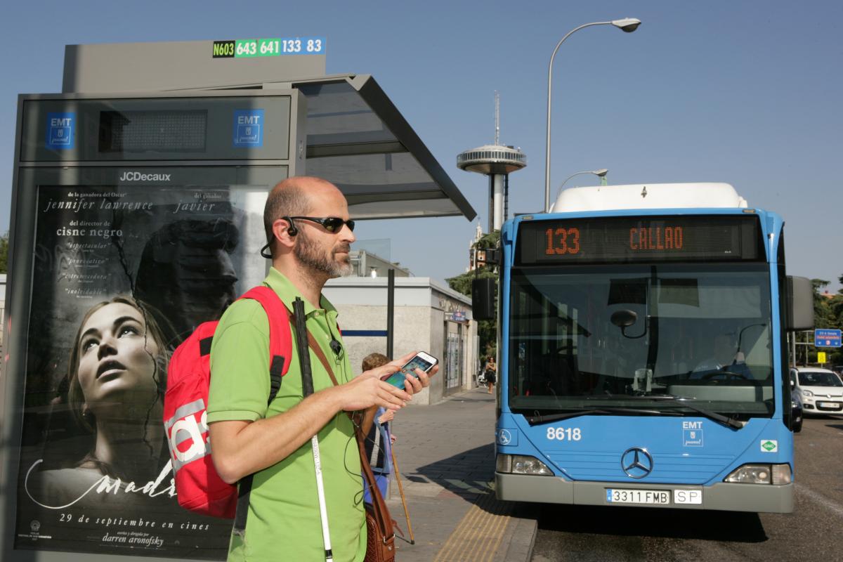 una persona ciega utiliza su móvil para recibir información sobre la llegada de su autobús