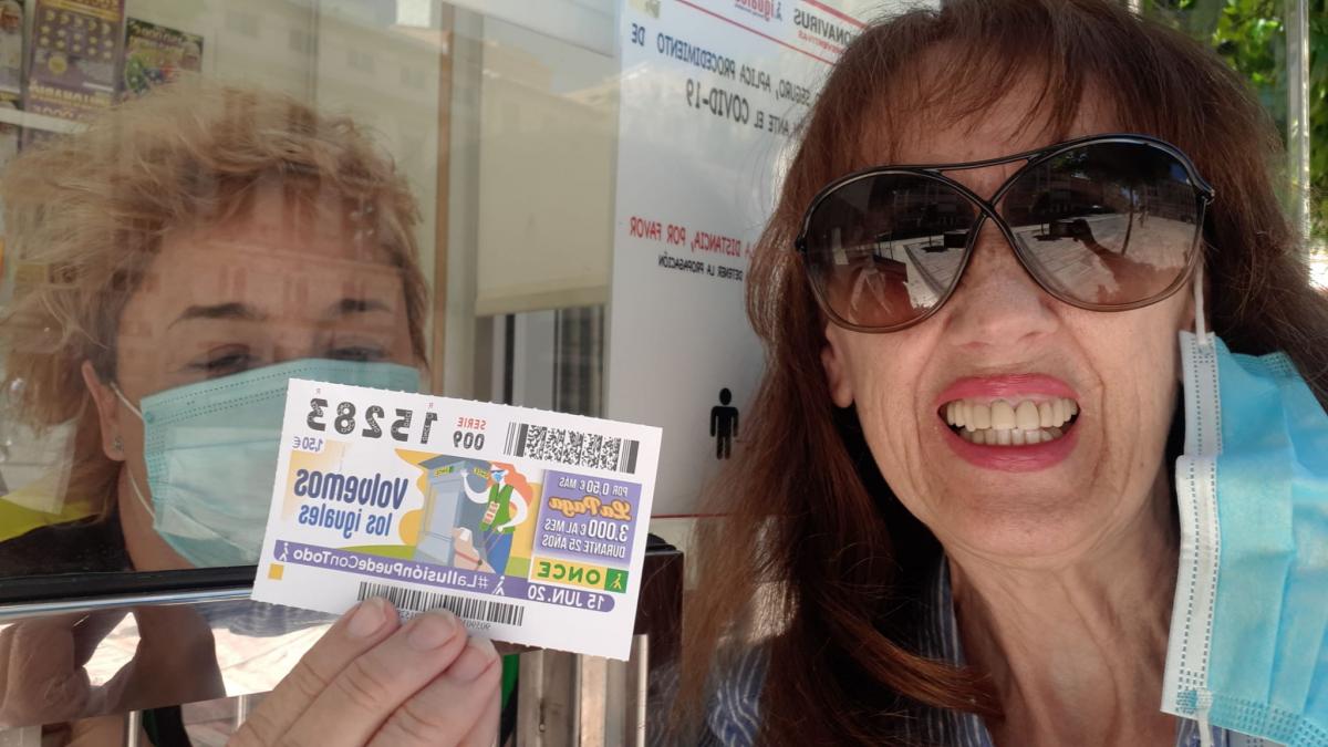 La periodista Carmen Abenza compra el cupón a Rosalía Fernández en el kiosco de la Plaza de la Constitución de Málaga