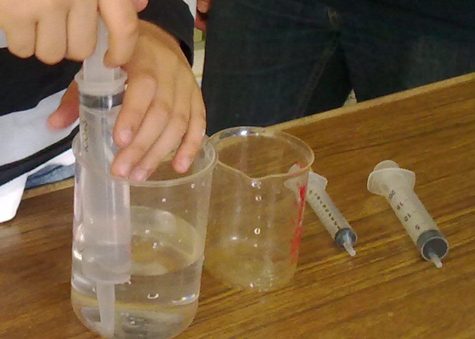 Alumno en el laboratorio midiendo la capacidad de un recipiente con una jeringuilla adaptada