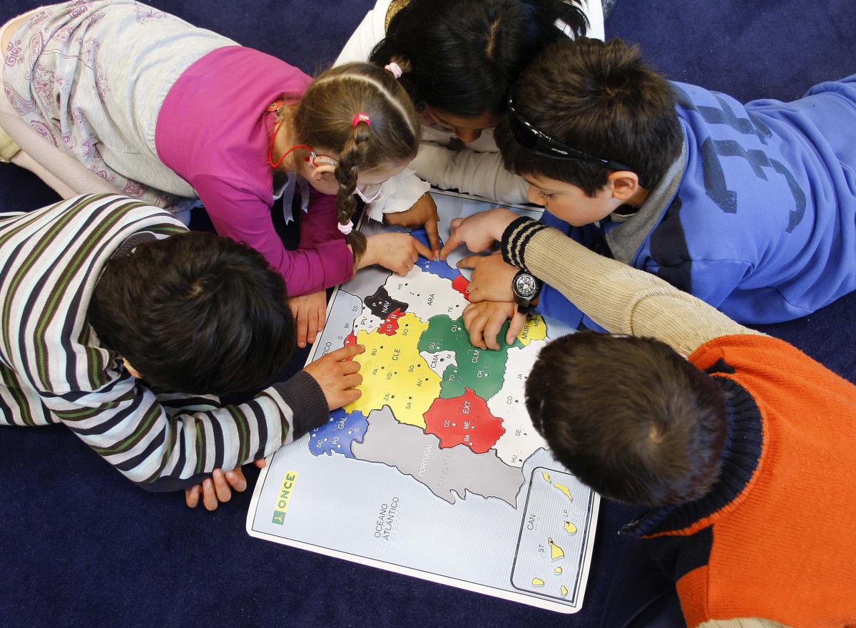 Alumnos estudiando con un mapa de España en braille