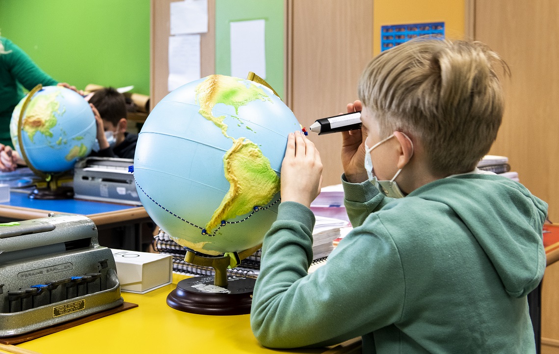 Un alumno manipula un mapa mundi en relieve