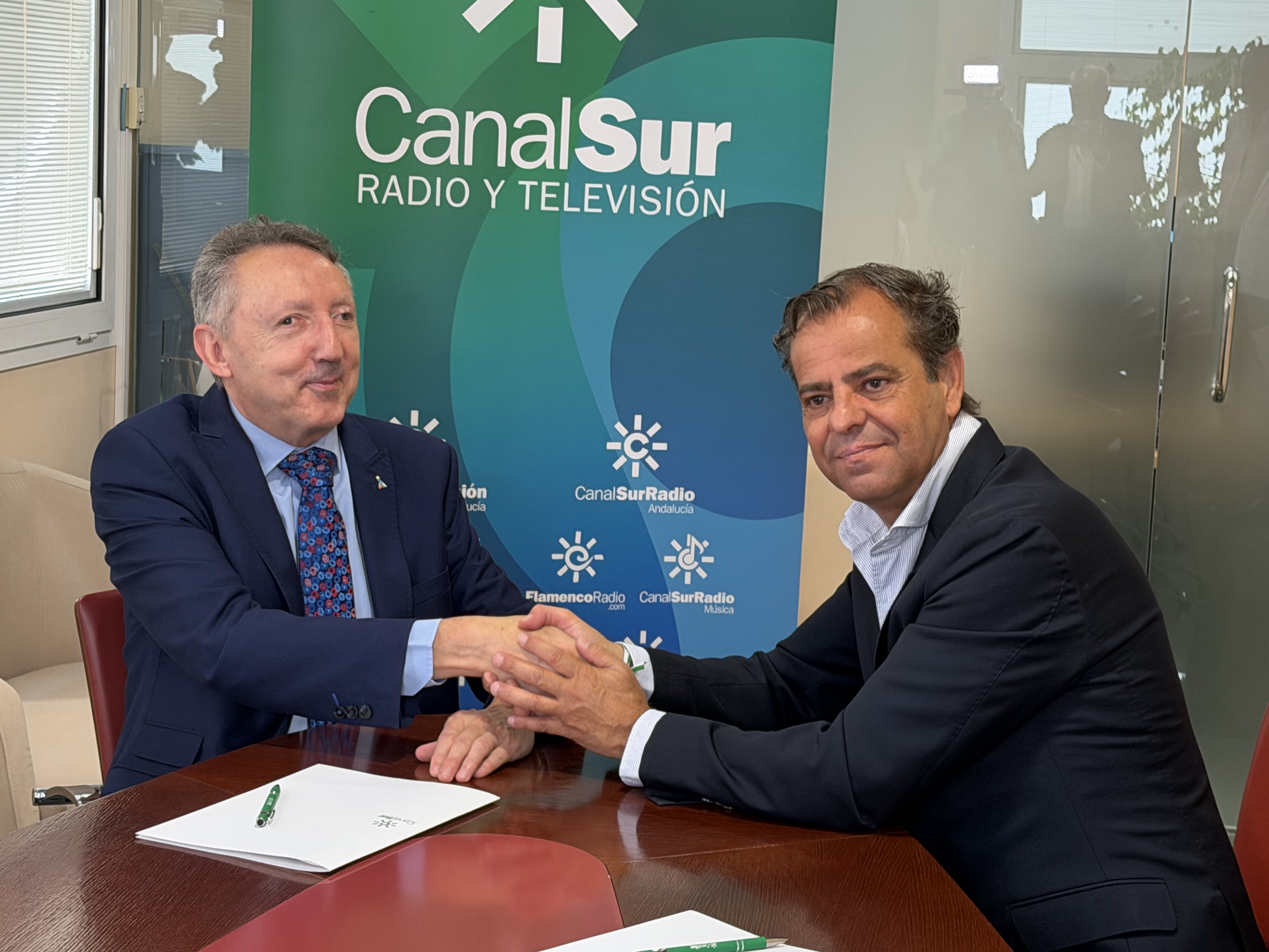 El delegado de la ONCE y el director general de la RTVA se saludan tras la firma del convenio