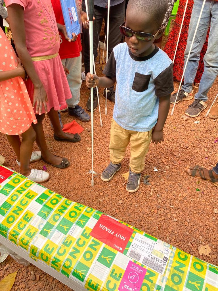 Un niño ciego junto a una de las cajas enviadas por la ONCE a Bafatá