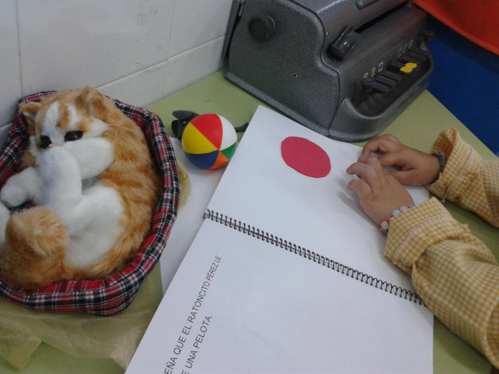 Las manos de una niña leen el cuento en braille