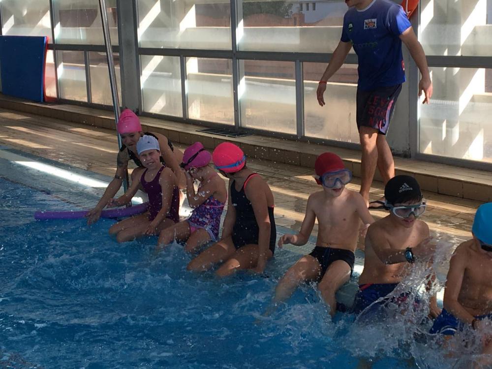 Alumnos batiendo piernas en el bordillo de la piscicna