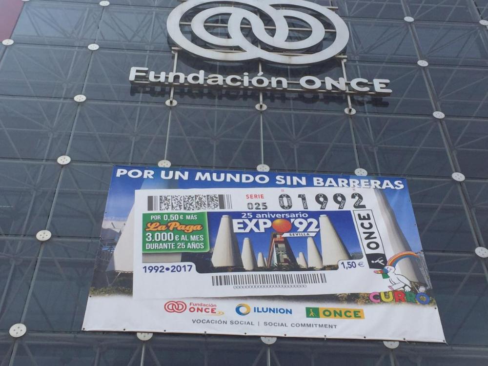 Una lona conmemorativa del 25 aniversario luce en la fachada principal del Pabellón de Fundación ONCE e ILUNION en la Isla de la Cartuja