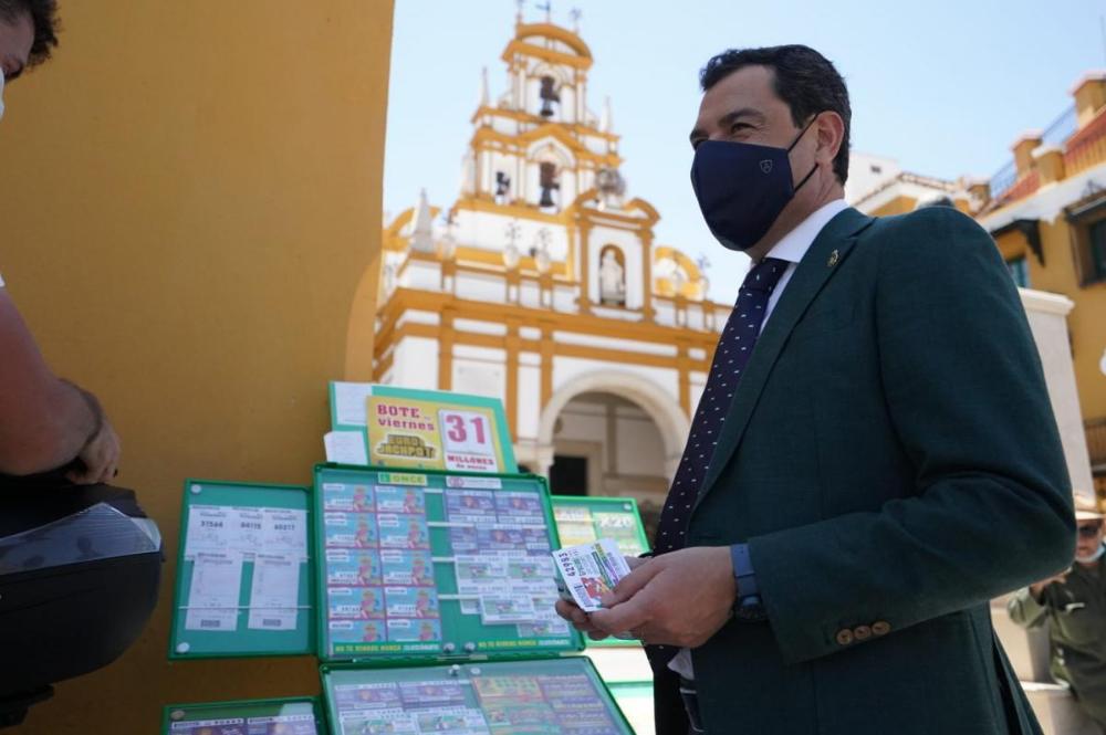 El presidente de la Junta de Andalucía, Juanma Moreno, compró cupones a Alberto Ferrer, en el Arco de la Macarena de Sevilla