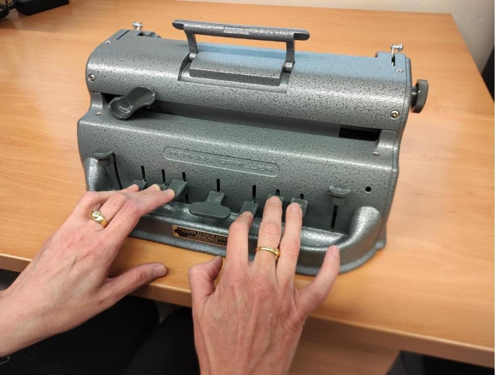 Una usuaria escribe con una máquina Perkins