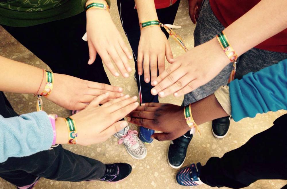 Manos enlazadas, manos diferentes, luciendo las pulseras del Concurso Escolar de la ONCE y su Fundación
