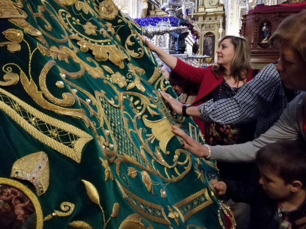 Un grupo de afiliados tocan el manto de la Esperanza en la parroquia de Santa de Granada