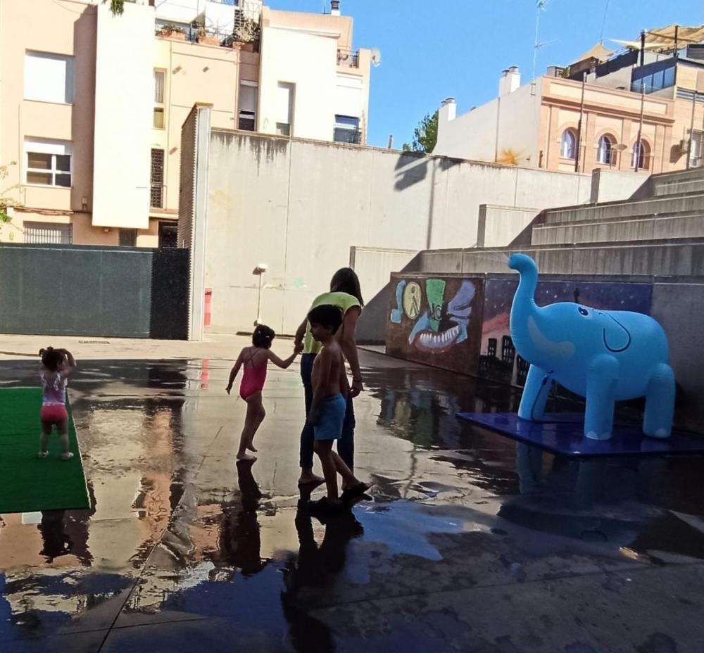 Padres, madres, niños y profesionales en círculo jugando con un plástico en movimiento simulando el sonido de las olas