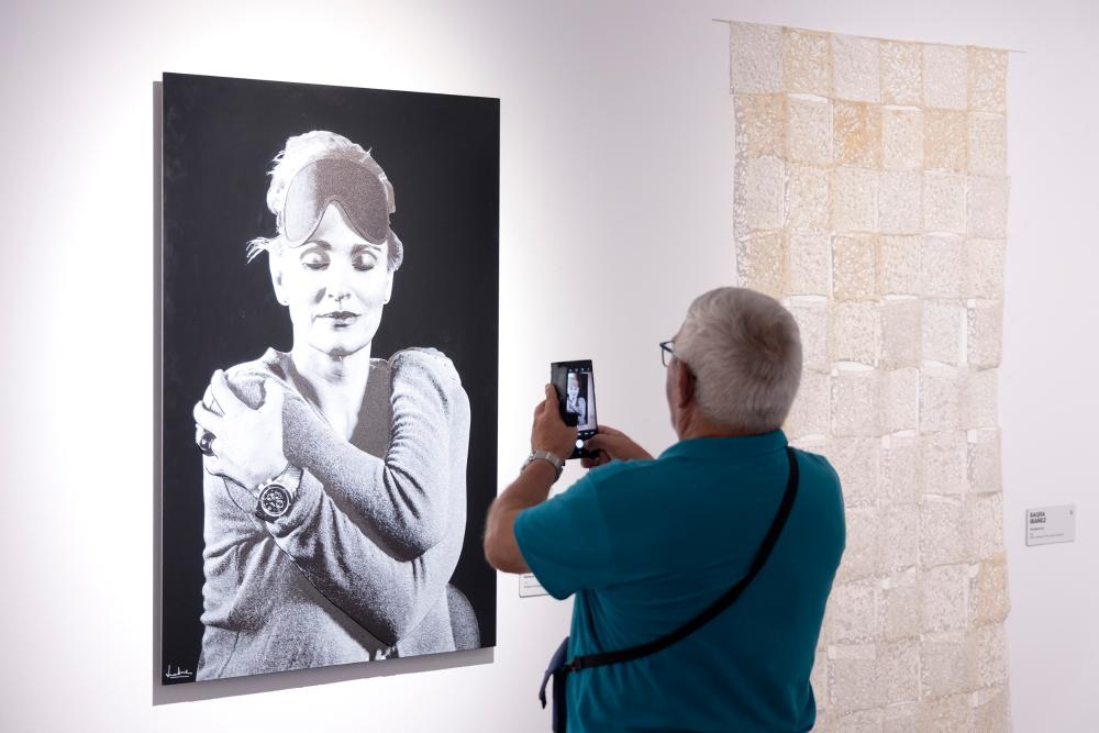Un espectador haciendo una foto con su móvil a uno de los cuadros