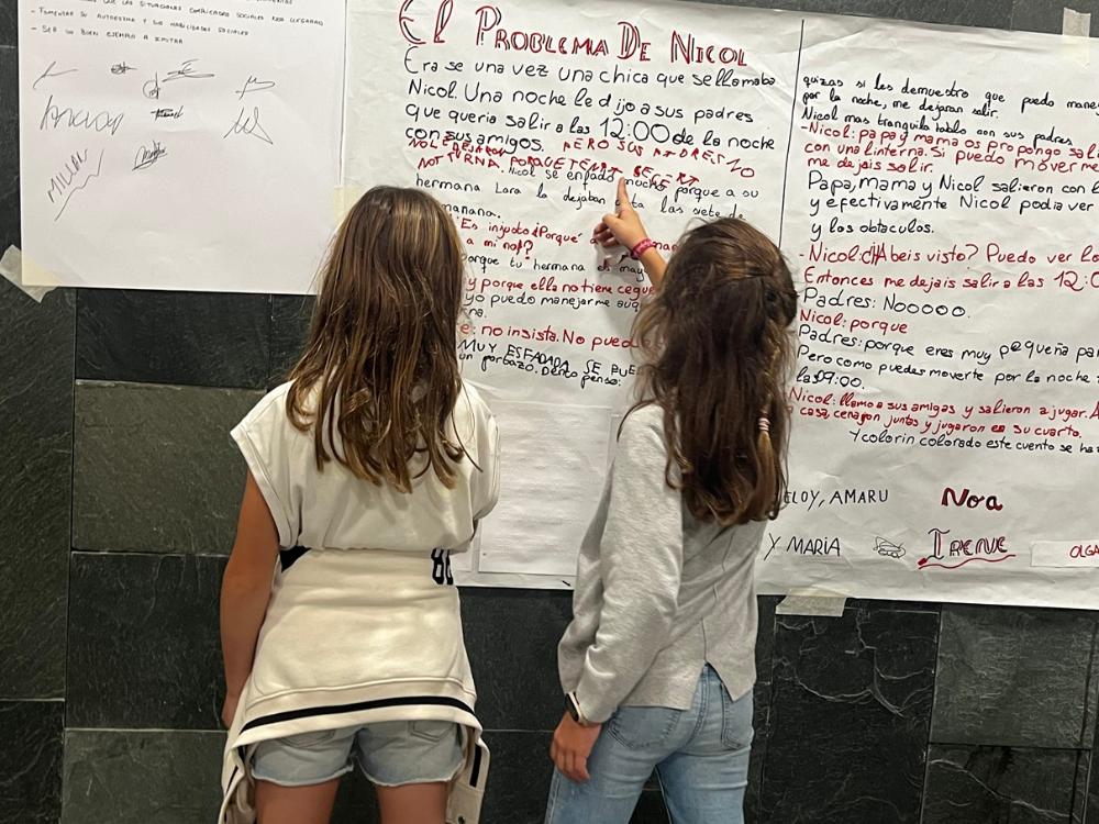 Dos alumnas de <secundaria observan los posters expuestos que fueron realizados por los alumnos durante los talleres