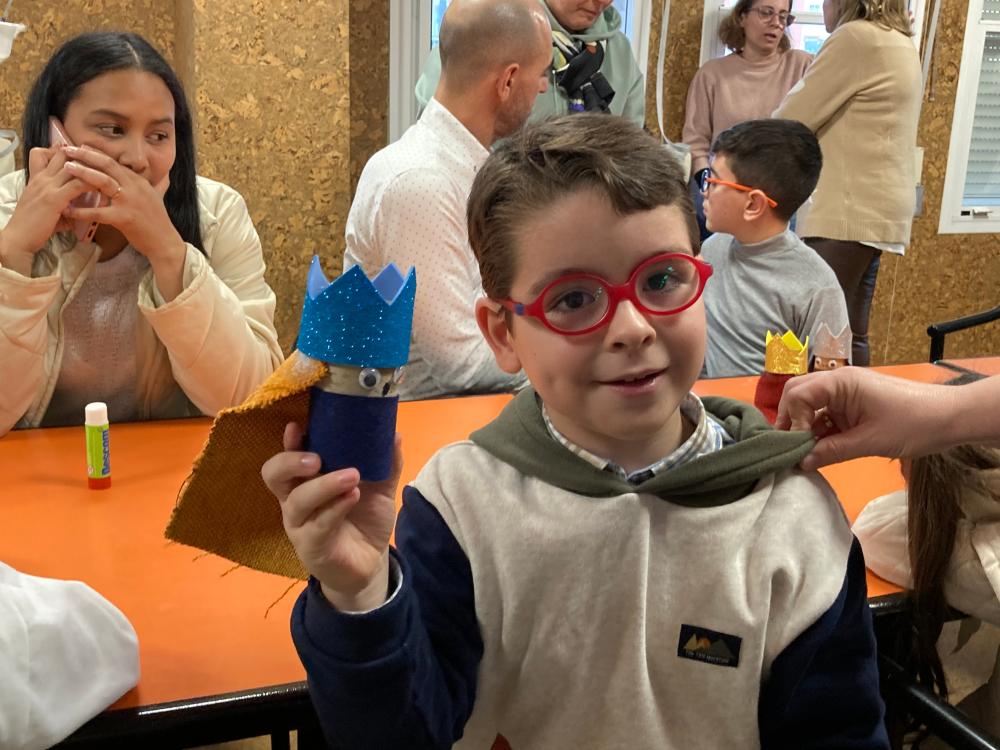 Un alumno muestra orgulloso la figura de un rey que ha elaborado con la ayuda de su madre