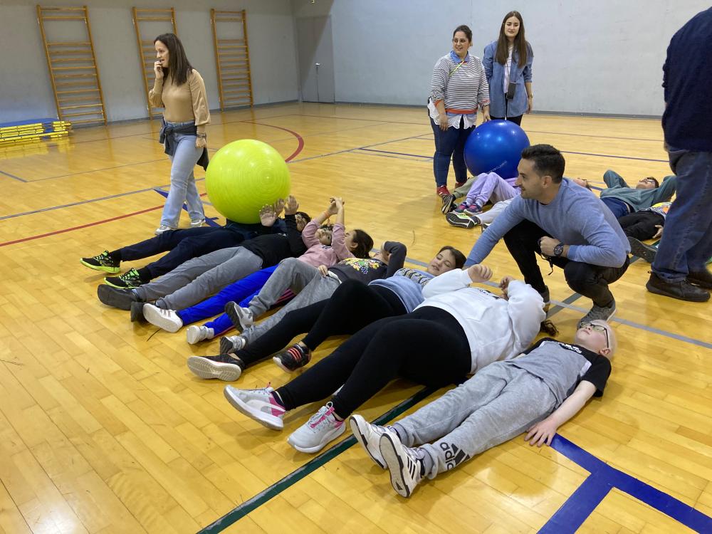 Juego de presentación con alumnos tumbados en el pabellón que se van pasando una pelota gigante al compañero de al lado