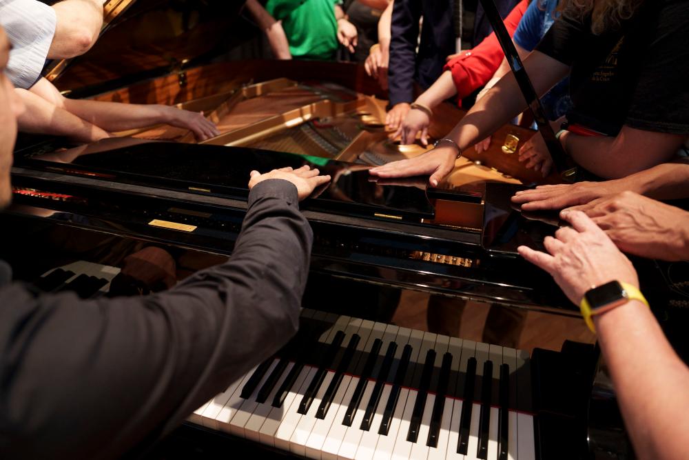 El pianista Víctor Gómez enseñando a los afiliados con sordoceguera el interior del piano