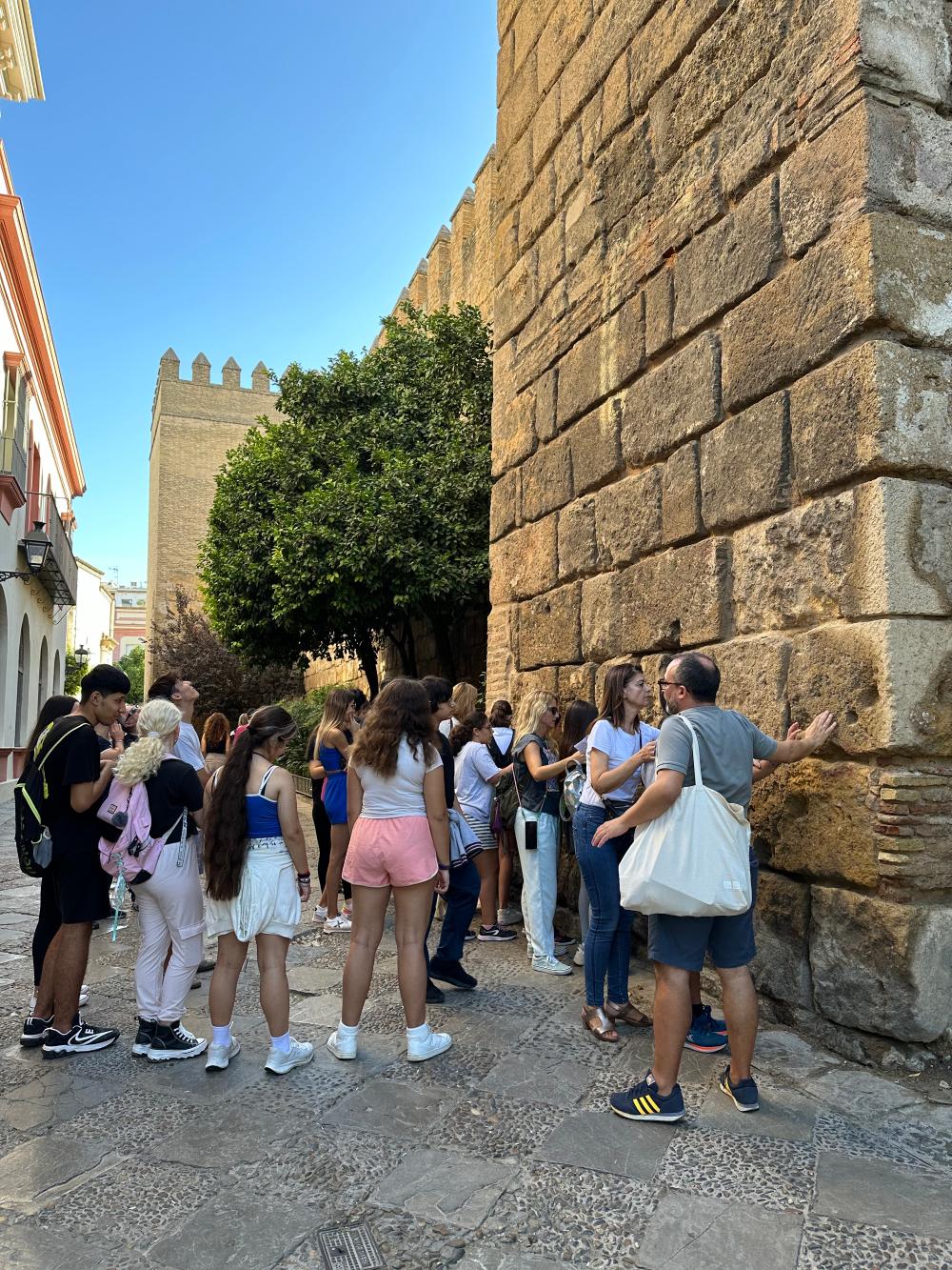 Participantes del tour guiado tocando la base de las murallas del Real Alcázar