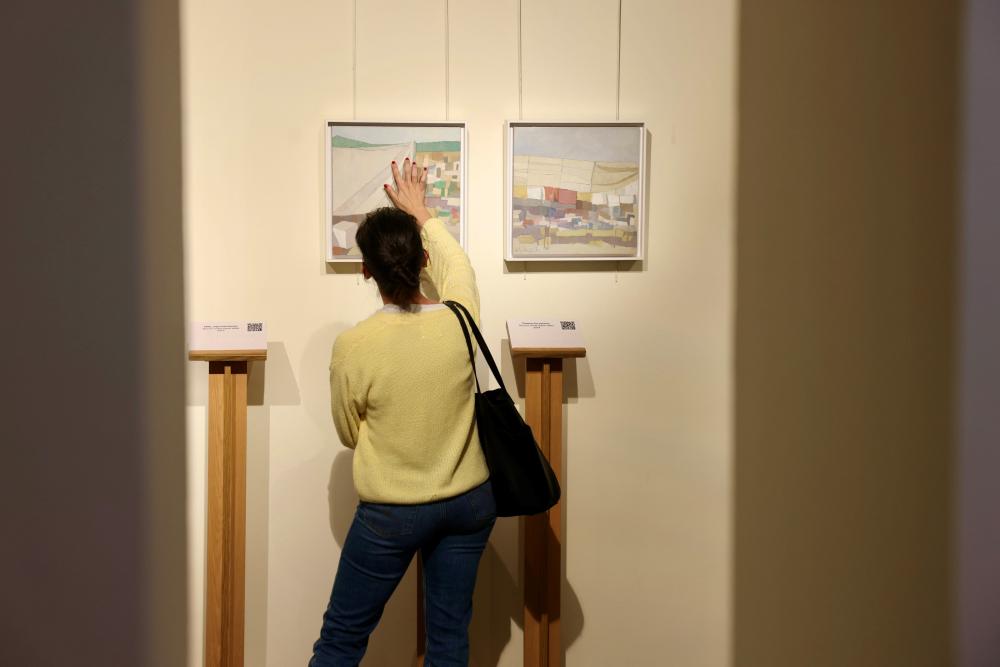 Una mujer toca el relieve de una de las pinturas de Molina Castro