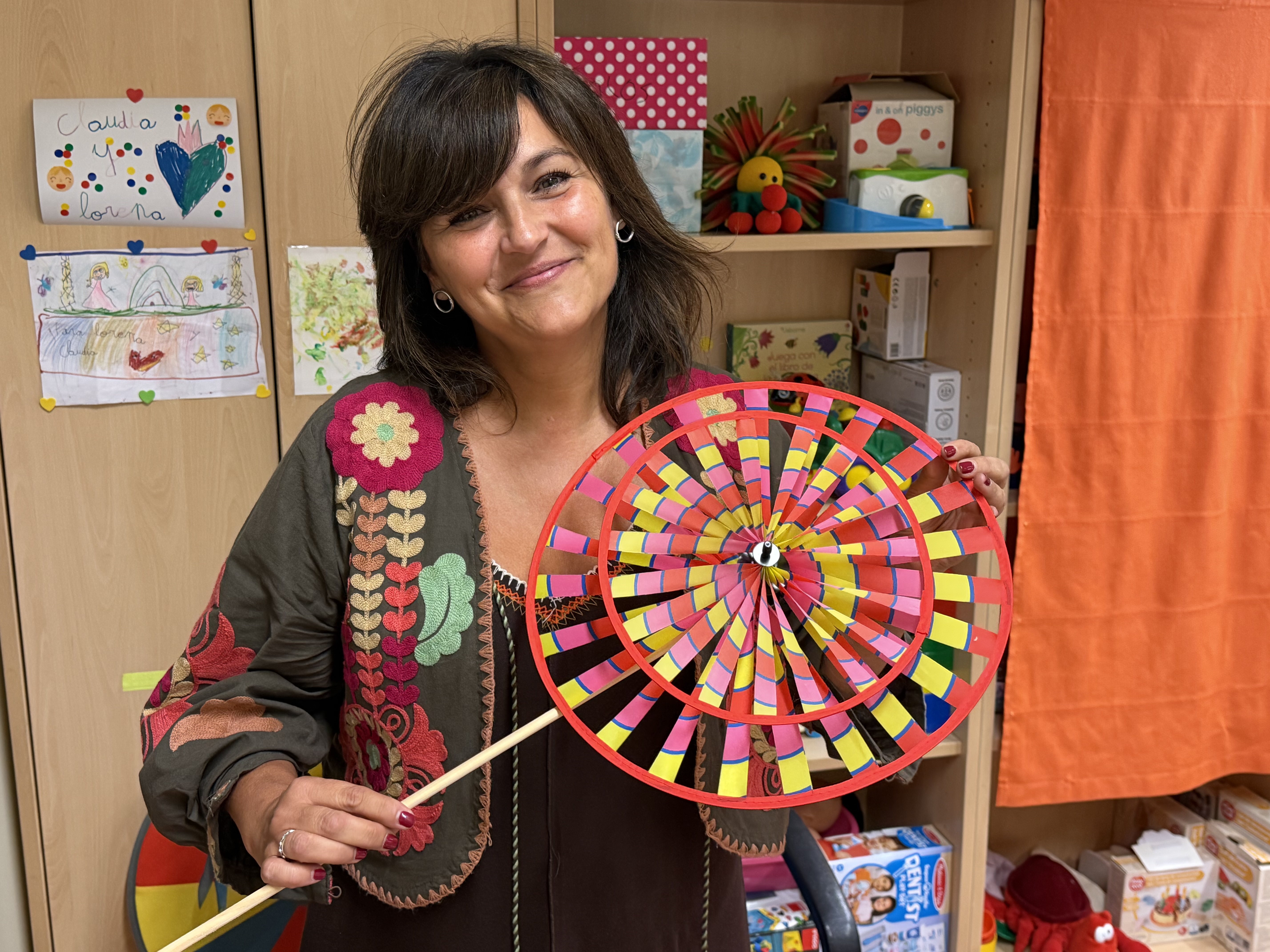 Primer plano sonriente de Mamen Hernández con una rueda giratoria de colores en la mano
